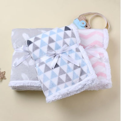 3 couvertures bébé bleue grise rose empilées