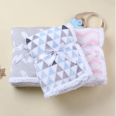 3 couvertures bébé bleue grise rose empilées