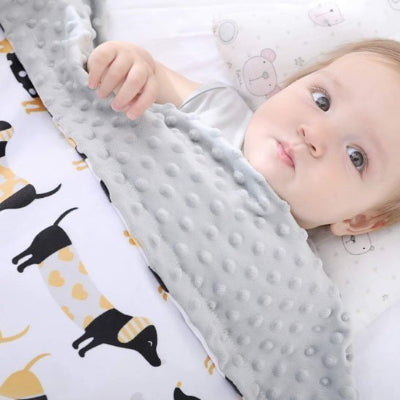 Bébé couché avec couverture bébé motifs chiens