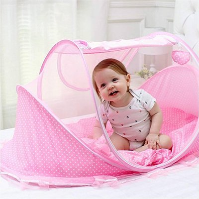 Bébé fille sourit assise dans LIT MOUSTIQUAIRE BEBE