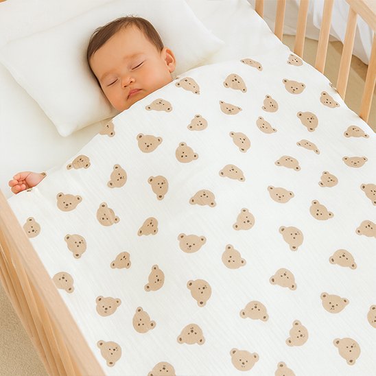 Bébé garçon couché avec couverture bébé blanc cassé ourson