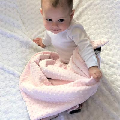 Couverture bébé rose sur jambes bébé assit