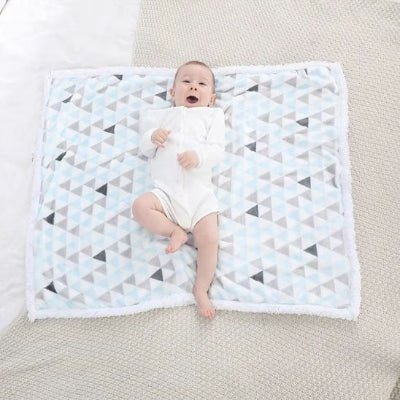 bébé qui rit couché sur couverture bébé