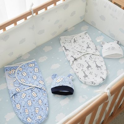 Couverture emmaillotage bonnet blanc et bleu dans lit bébé
