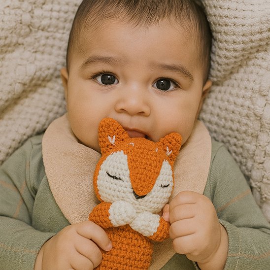 Bébé garçon couché qui serre doudou renard 